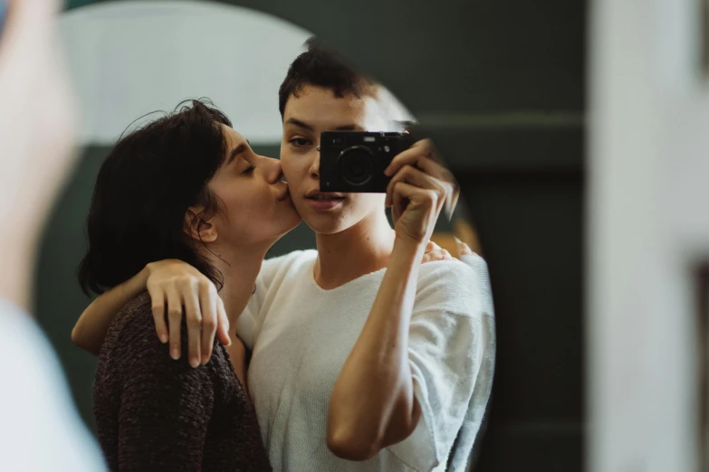 a young woman is kissing the man's face with her hand as he holds her