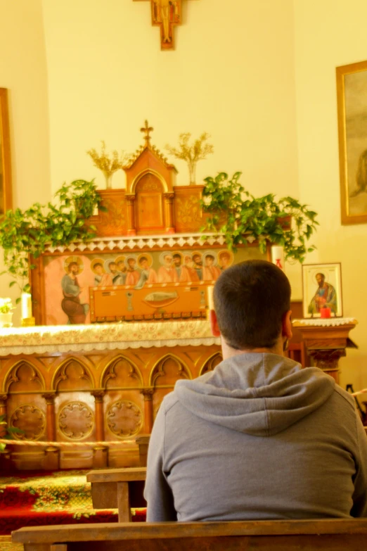 a person sitting in a church with an altar and other religious decorations