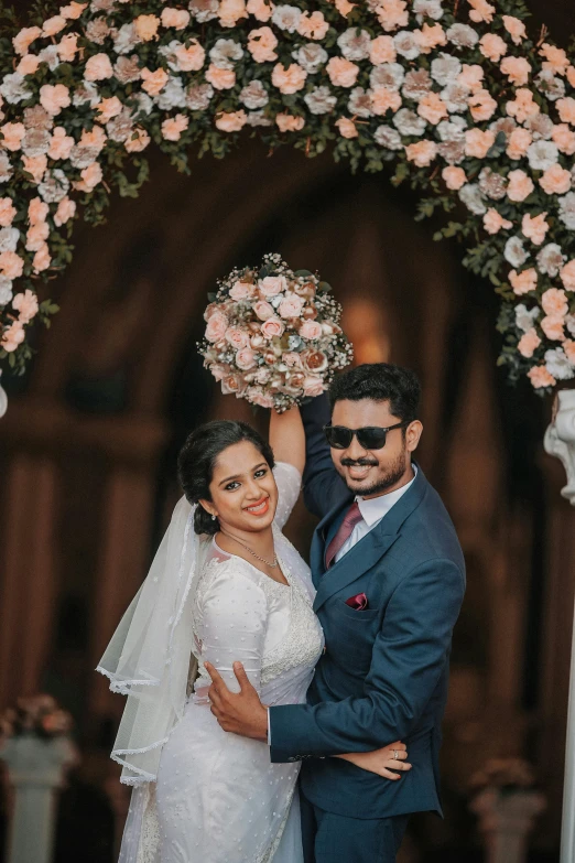 a newly married couple under a floral decorated arch