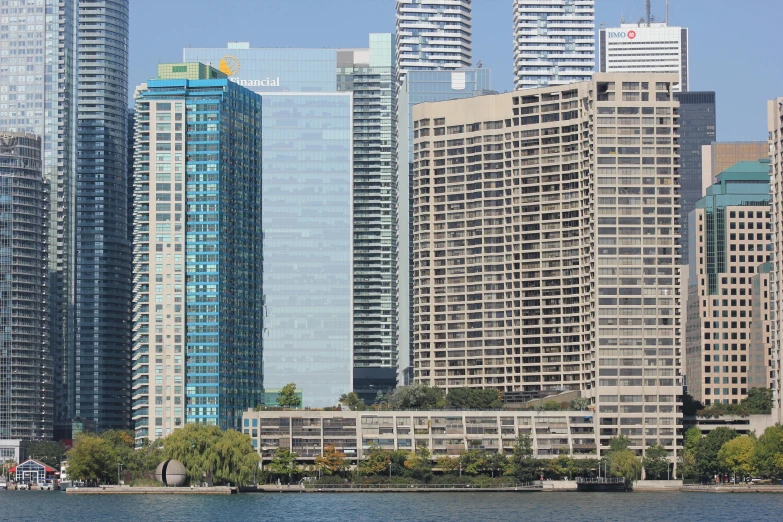 several large buildings next to a river with sailboats in the water