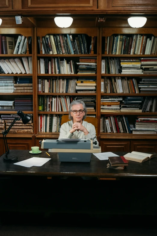 an older gentleman sitting in front of a desk with a typewriter