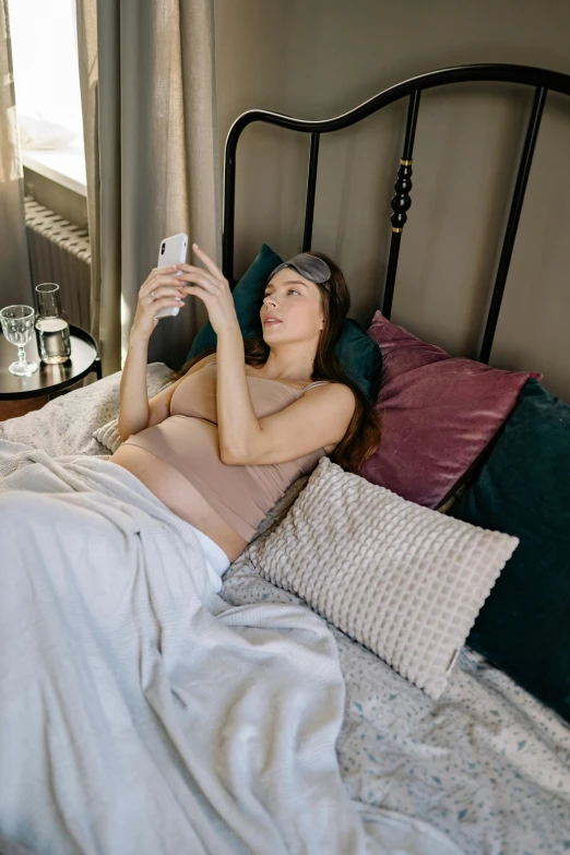 a woman laying in bed and holding up a cup