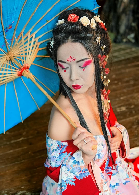 a geisha woman sits holding an umbrella