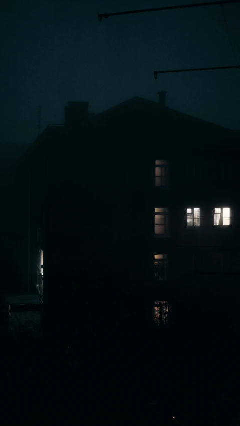 a dark building with three windows and no one outside