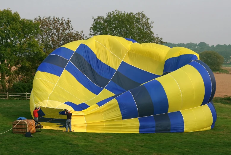 people flying a huge blue and yellow striped kite