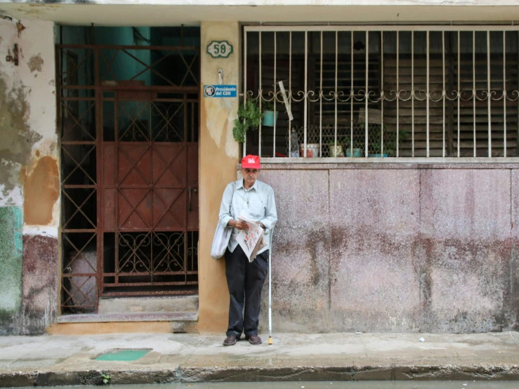 an older man is standing outside wearing his walking stick