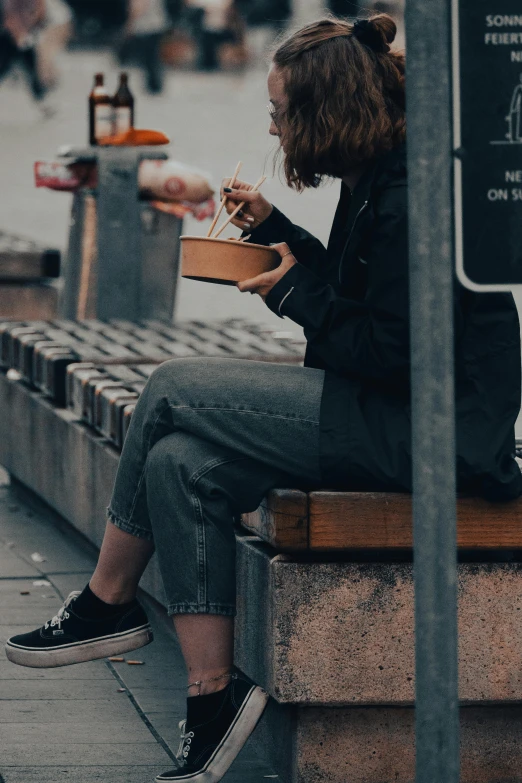 a woman sitting on a bench eating a piece of pizza