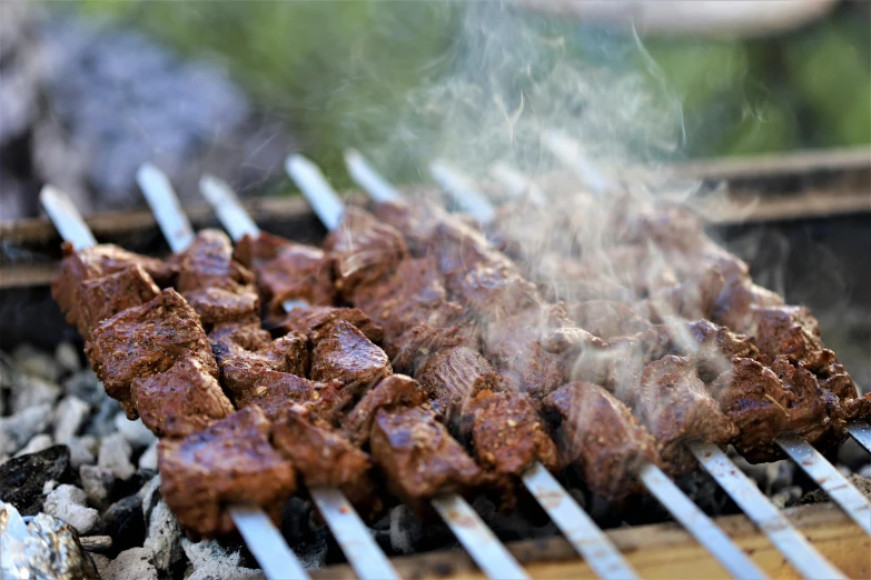 several pieces of meat sit on a grill, as smoke rises from it