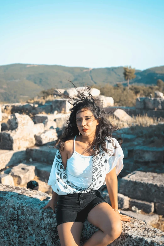 a woman posing for a po while sitting on rocks