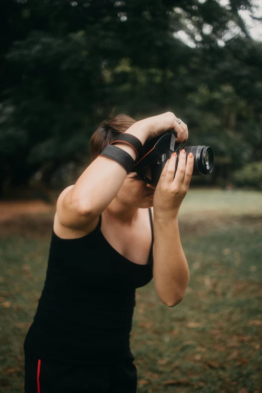 a woman wearing black takes pictures with a camera