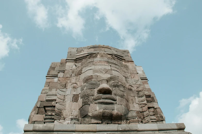 a very tall brick structure with a giant face at the top