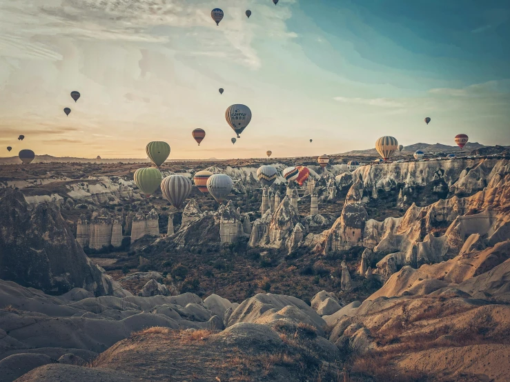 some  air balloons in the sky over the rocky terrain