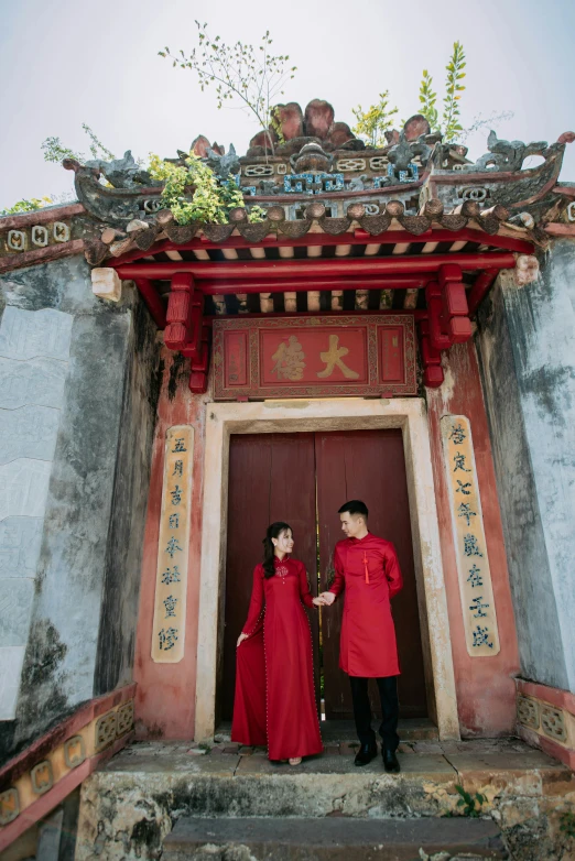 two people in red dress standing outside the doorway to a large building