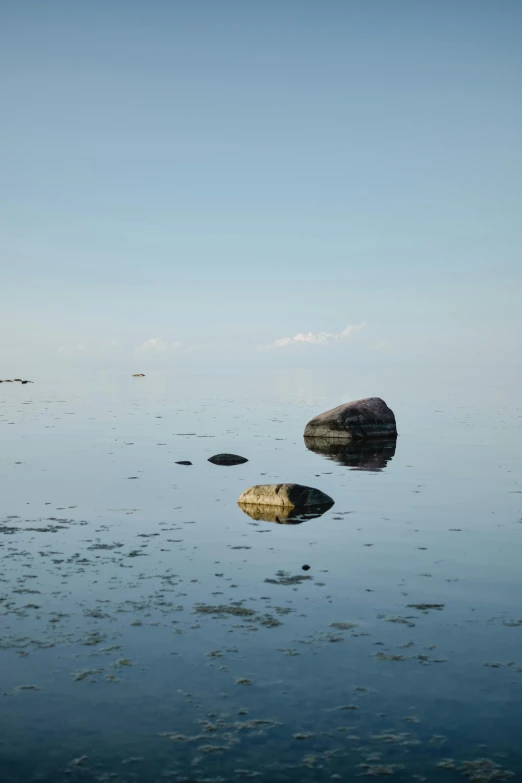 two rocks in water with a clear sky above