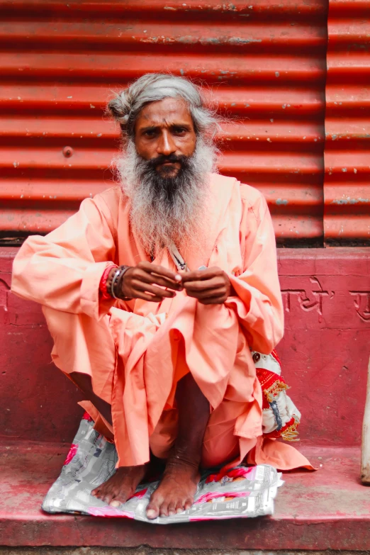 a man with a long beard and white beard sitting on the street