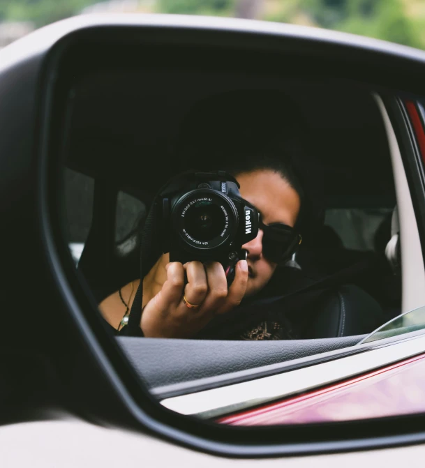 woman taking po from car window in mirror