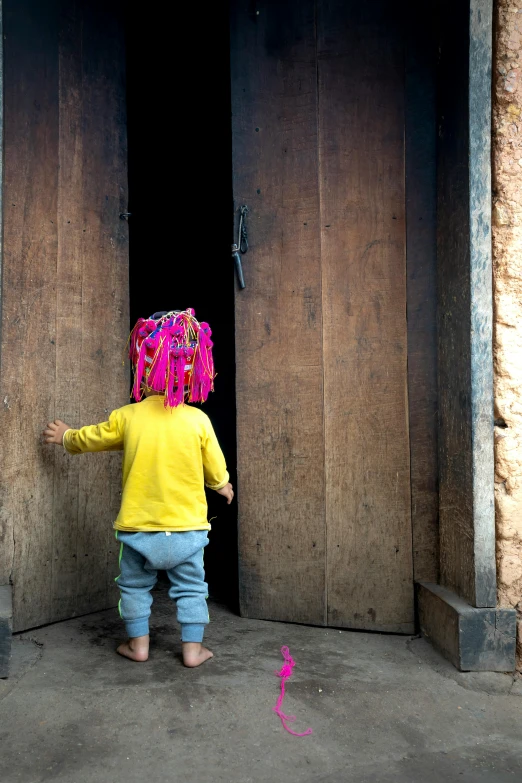 a young child with colorful decorations on her head looking at a pink object