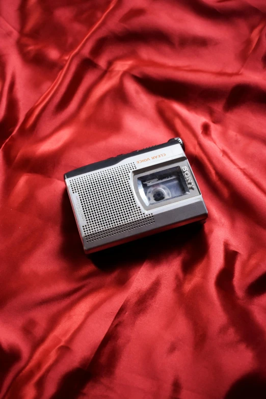 a radio sitting on a red cloth on the ground