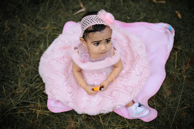 a young doll is sitting on a blanket