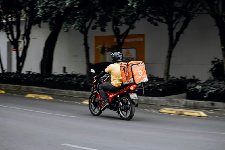 a motorcyclist wearing a bike and carrying a large bag behind him