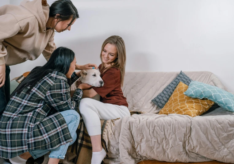 two woman are petting a  as she is petting her goat