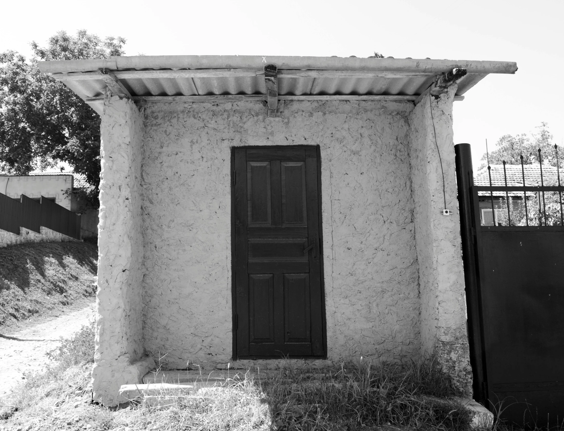 a black and white po of an outhouse on the edge of a field