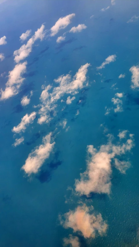 an aerial view of the blue ocean with white clouds