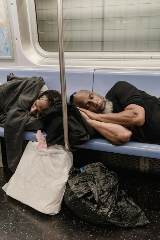 an elderly man sleeping on a train next to bags