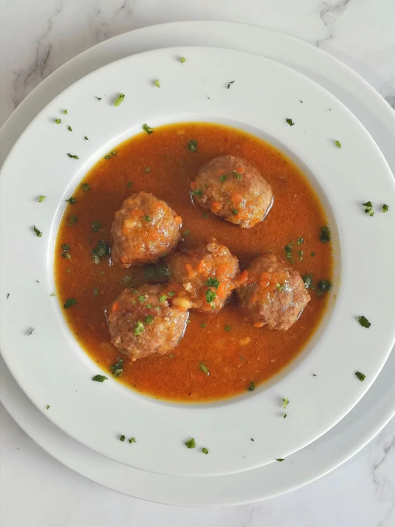 a white plate topped with meatballs in a tomato sauce