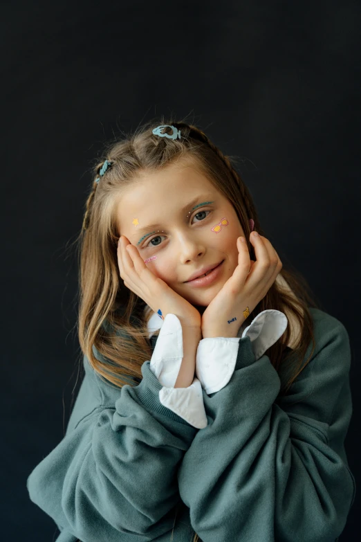 girl wearing dress smiling while posing with her hands near her face