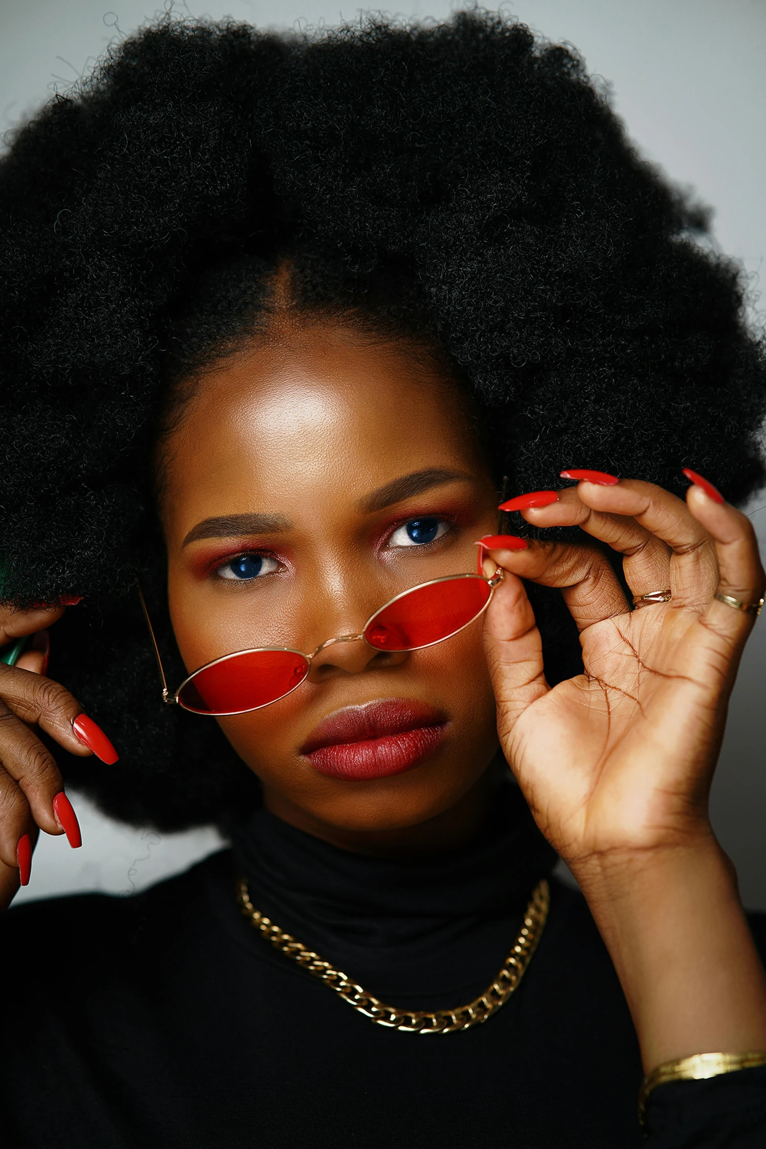 a woman wearing a pair of glasses and red nails with her hands on her head