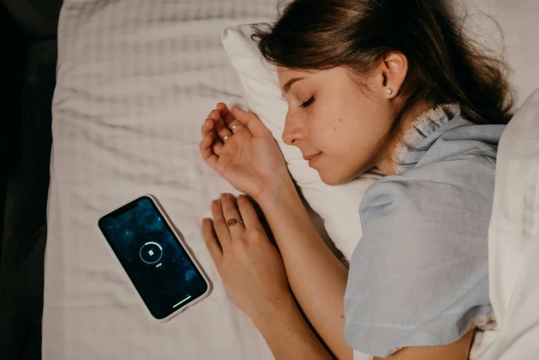 a woman laying in bed next to a phone