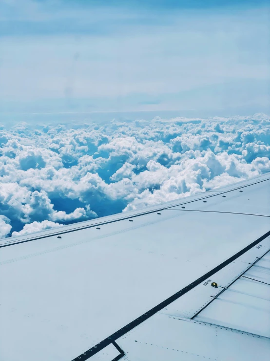 the airplane wing is above a cluster of clouds