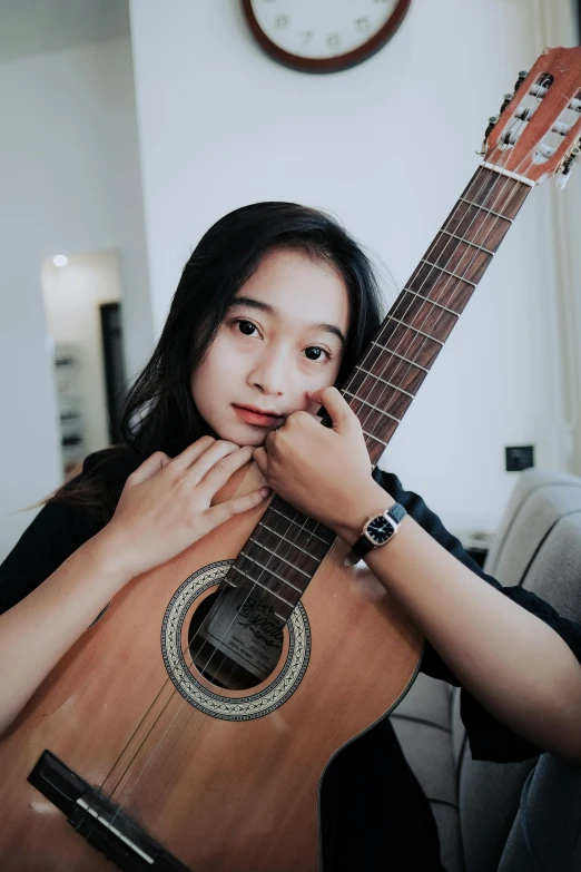 a young asian girl holding an acoustic guitar