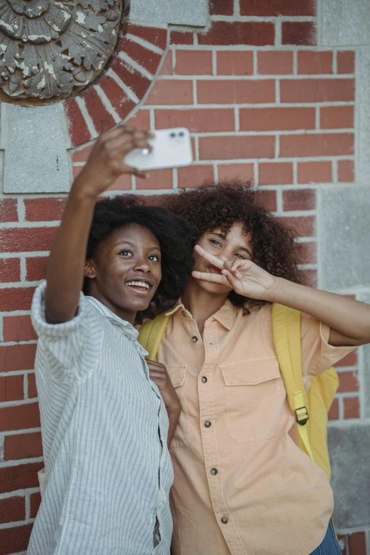 two women that are standing in front of a wall