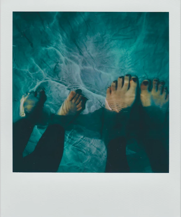 a man and woman's feet floating in a pool of water