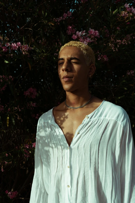 a young man posing for a pograph in front of some flowers