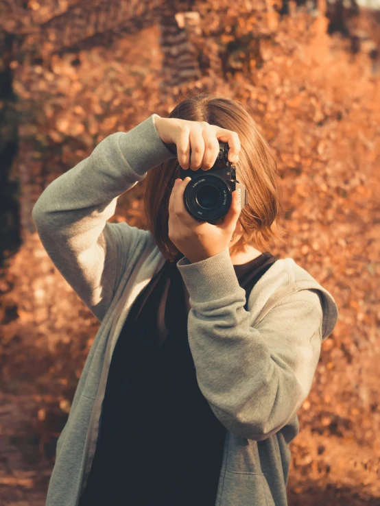 woman taking pograph with digital camera in front of rocky terrain