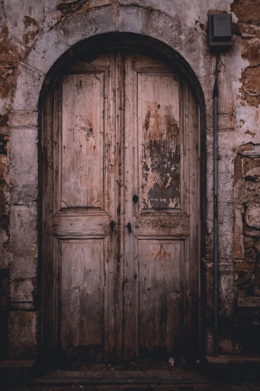 an old building with two wood doors and one brick wall