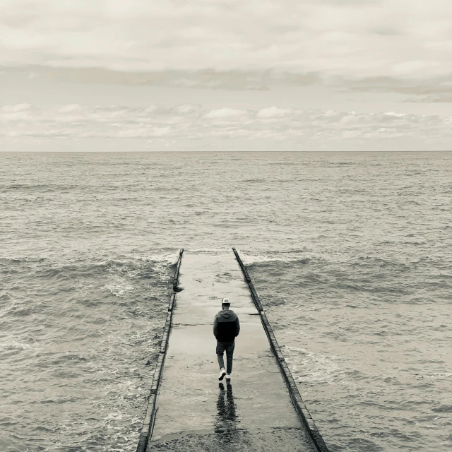 a person walking along a wooden pier in front of the water