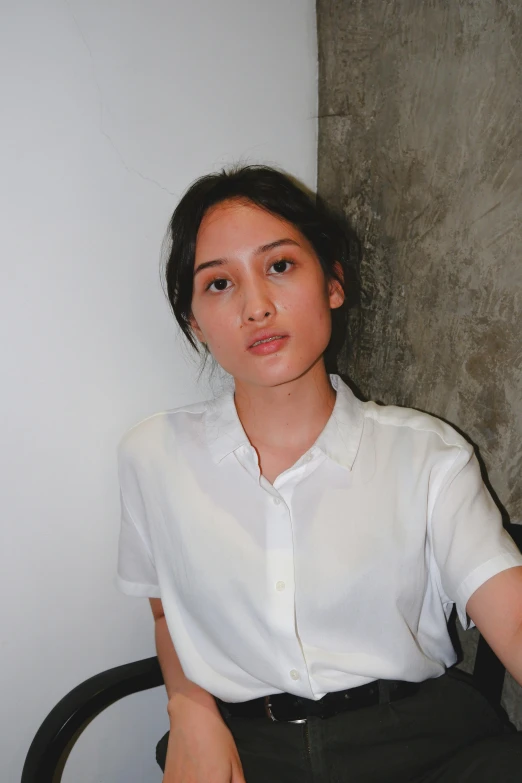 a woman posing in a white shirt and black pants