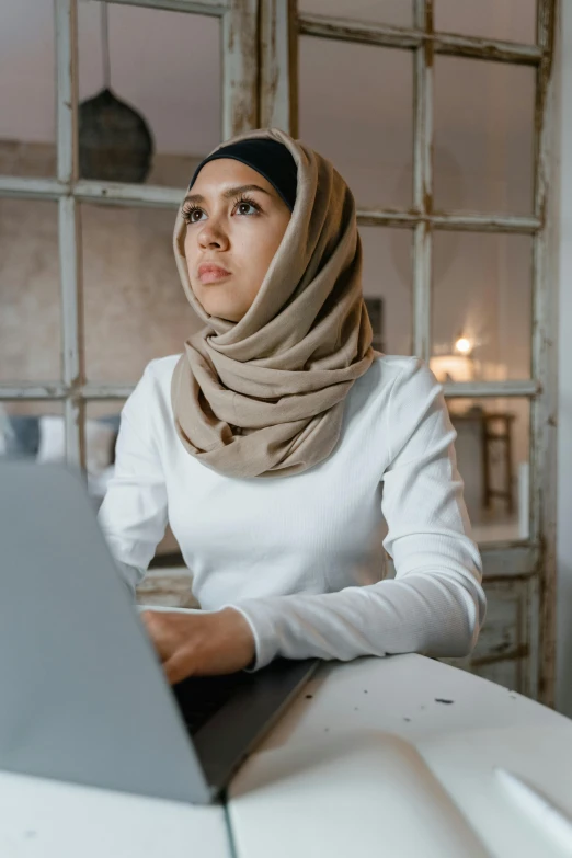 a woman wearing a white shirt and a beige scarf is sitting in front of a table