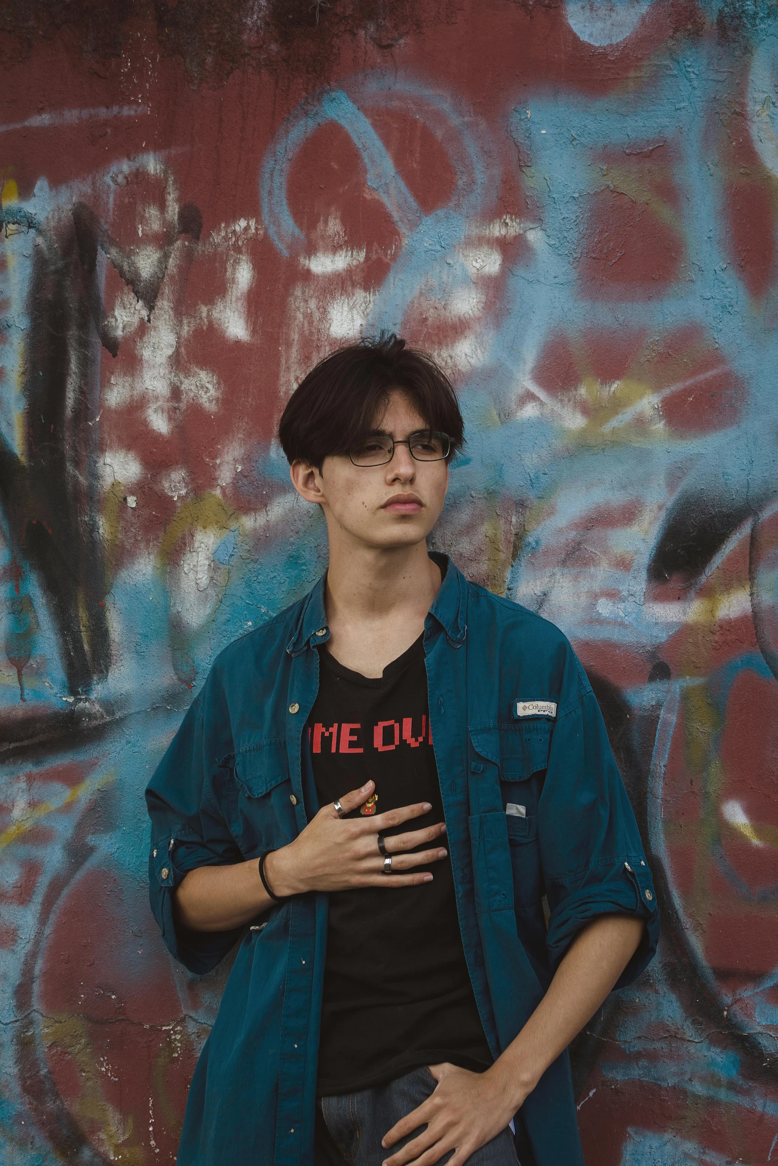 a man standing in front of a wall covered in graffiti