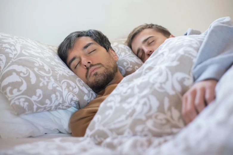 a couple of people laying in bed under pillows