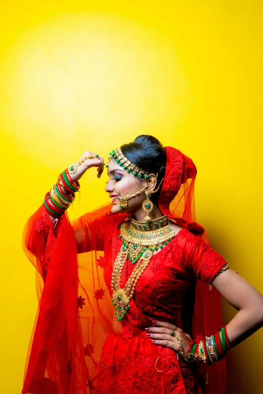 a woman in a red bridal gown stands against a yellow background