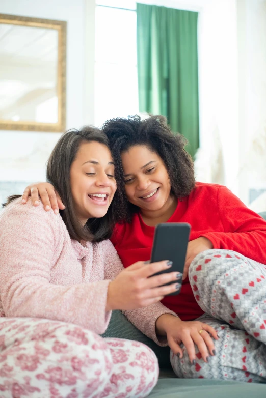 two beautiful women looking at a cell phone together