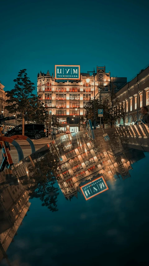 the night scene shows the reflection of a building on a mirror like surface