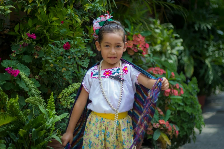 a little girl is standing near a bush