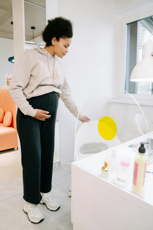 woman in gray sweatshirt and black pants standing near beauty counter