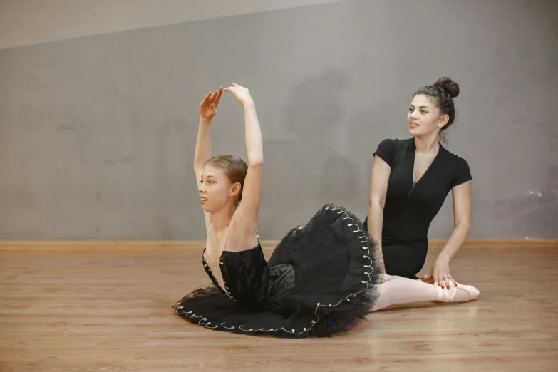 two dancers sit on the ground in front of each other